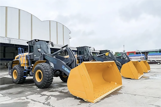 Used wheel loaders lined up outside a warehouse